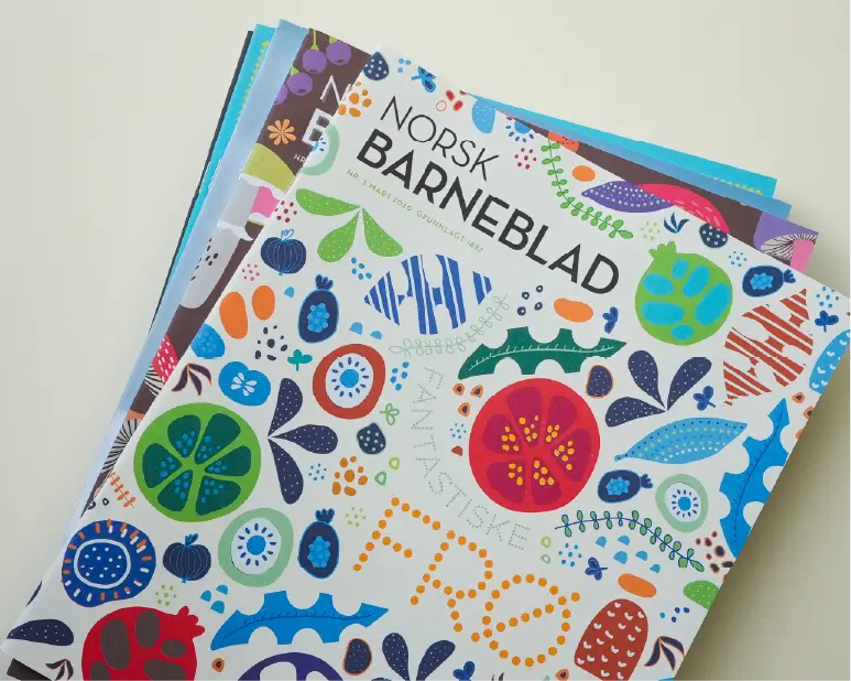 Ein bunke med utgåver av Norsk Barneblad, med forsida til nr. 3/2020 (Frø) øvst, som illustrerer kva abonnementet inneheld.
